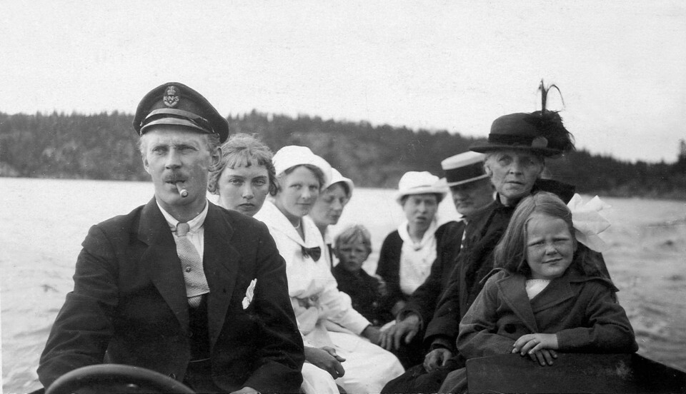 JAC M. IVERSEN:  Jac M. Iversen med sin sigar sitter til rors i en av sine motorbåter en gang i 1918 sammen med sin familie. Fra høyre er hans niese, mor,  en ukjent mann, kona Signe, to søstre og to ukjente.
