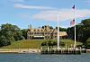 Historisk klubbhus for New York Yacht Club ved vannet i Newport, med brygge, seilmaster og amerikanske flagg.
