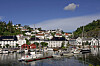 Båter ligger ved kai foran hvite hus og en liten havn i Tvedestrand.