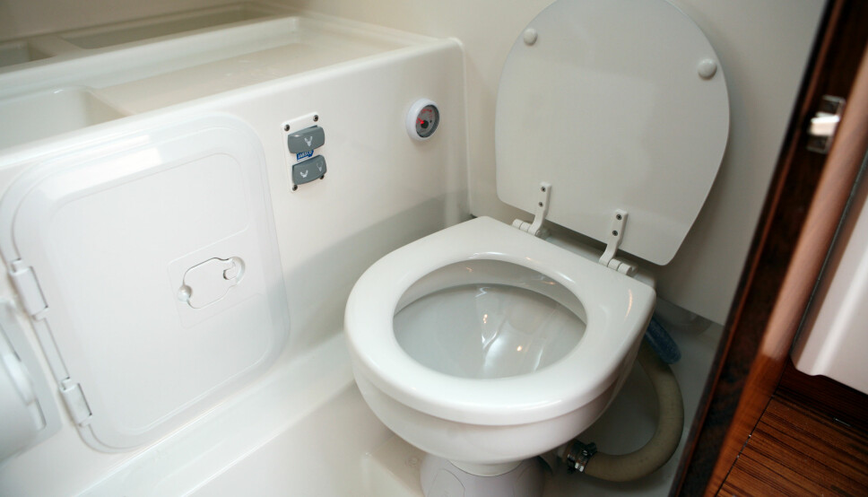 KONVERTERT: Den gamle toalettskålen plassert på den nye, elektriske pumpen. Toalettlokket kan åpnes fritt og har en bra vinkel mot skottet. Holder man inne den øverste knappen på betjeningspanelet, så sørger automatikken for tømming og spyling av toalettet.