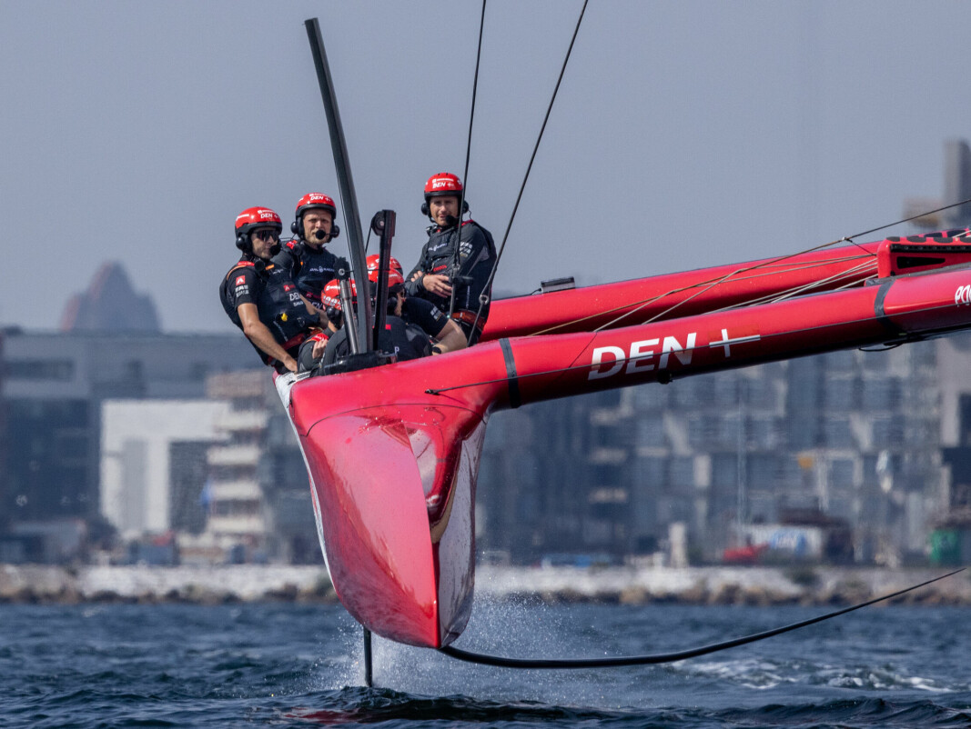 Kevin Magnussen, Formula One driver for Haas F1 Team, takes the wheel as he sits alongside Nicolai Sehested, driver of Denmark SailGP Team, after joining the Denmark SailGP Team presented by ROCKWOOL as a sixth sailor during a practice session ahead of the ROCKWOOL Denmark Sail Grand Prix in Copenhagen, Denmark. 15th August 2022. Photo: Felix Diemer for SailGP. Handout image supplied by SailGP