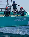 Tre seilere i SailGP-båt i høy fart på sjøen med turkis skrog.
