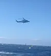 Helikopter flyr lavt over bølgete hav under operasjon