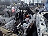 Seilbåter ligger tett ved bryggen i en marina med mye tauverk og båtutstyr.