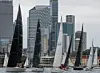 Seilbåter i forgrunnen med moderne skyskrapere og kontorbygg i bakgrunnen.