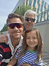 Tre personer poserer for en selfie foran en moderne bygning.