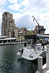 Seilbåter fortøyd ved en brygge foran moderne boligbygg og vann.