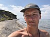 Bror Sonne står solbrun på en strand på tunø i danmark. Han har på caps. bak er en klippe. landskapet er fremmed, langt hjemmefra