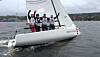 SEILSPORT: Et seilerlag jubler om bord etter en regatta, med den norske kystlinjen i bakgrunnen.